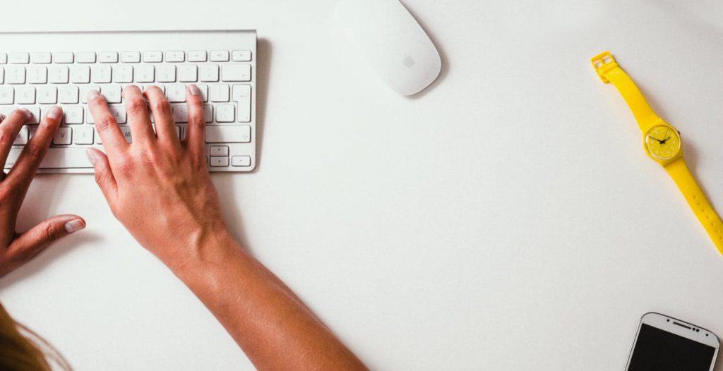 man typing out a blog post on keyboard